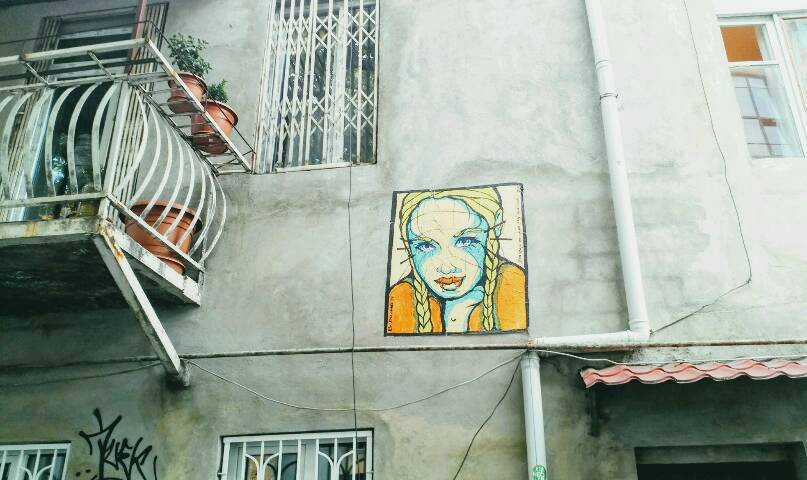 Gelbe Frau schaut von Hauswand