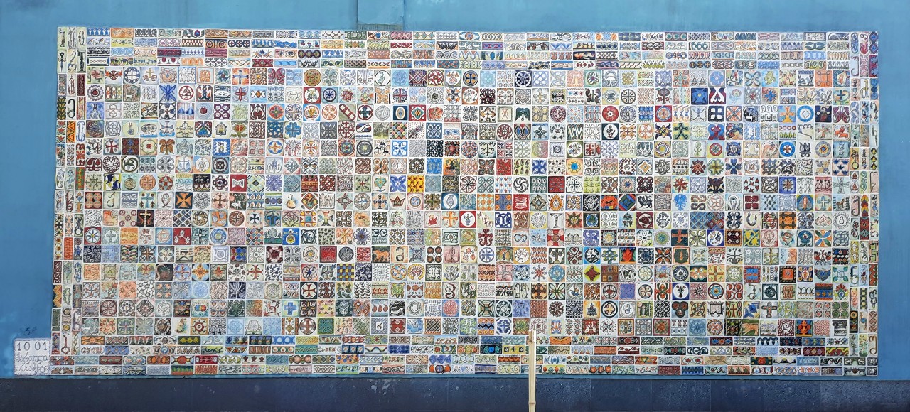 Eine grosse Tafel mit hunderten georgischen ornamenten ziert eine Hauswand in Gori